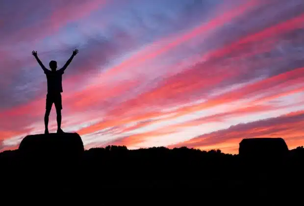 silhouette of man standing on high ground under red and blue skies